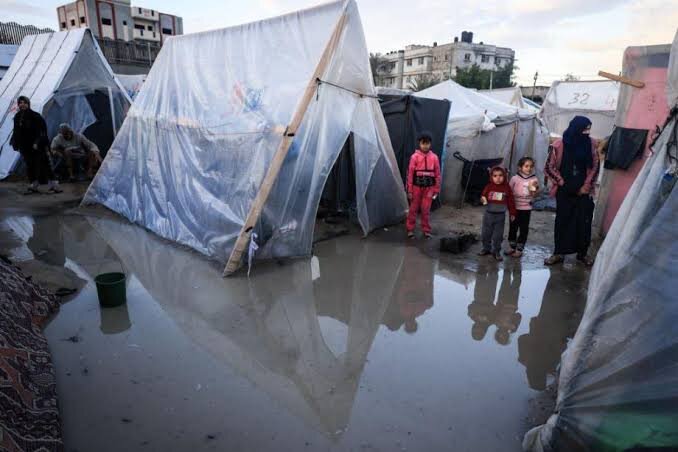 A mother and her children inside a worn shelter in Gaza